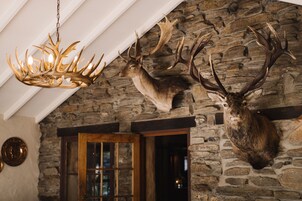 A stone wall with mounted deer heads and a chandelier.