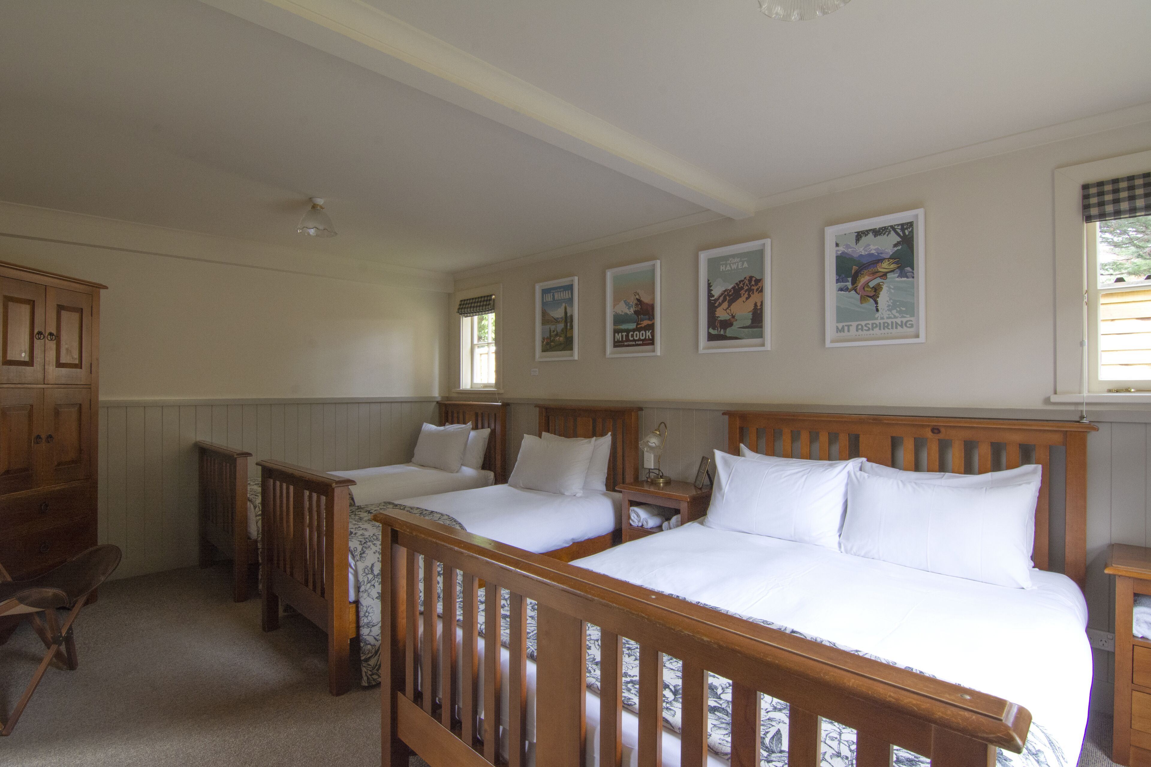 A bedroom with two wooden beds, a wooden dresser, and a window with blinds.