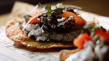 A close-up of a dish with a variety of toppings, including vegetables and possibly some grains or seeds, on a flatbread or similar base.