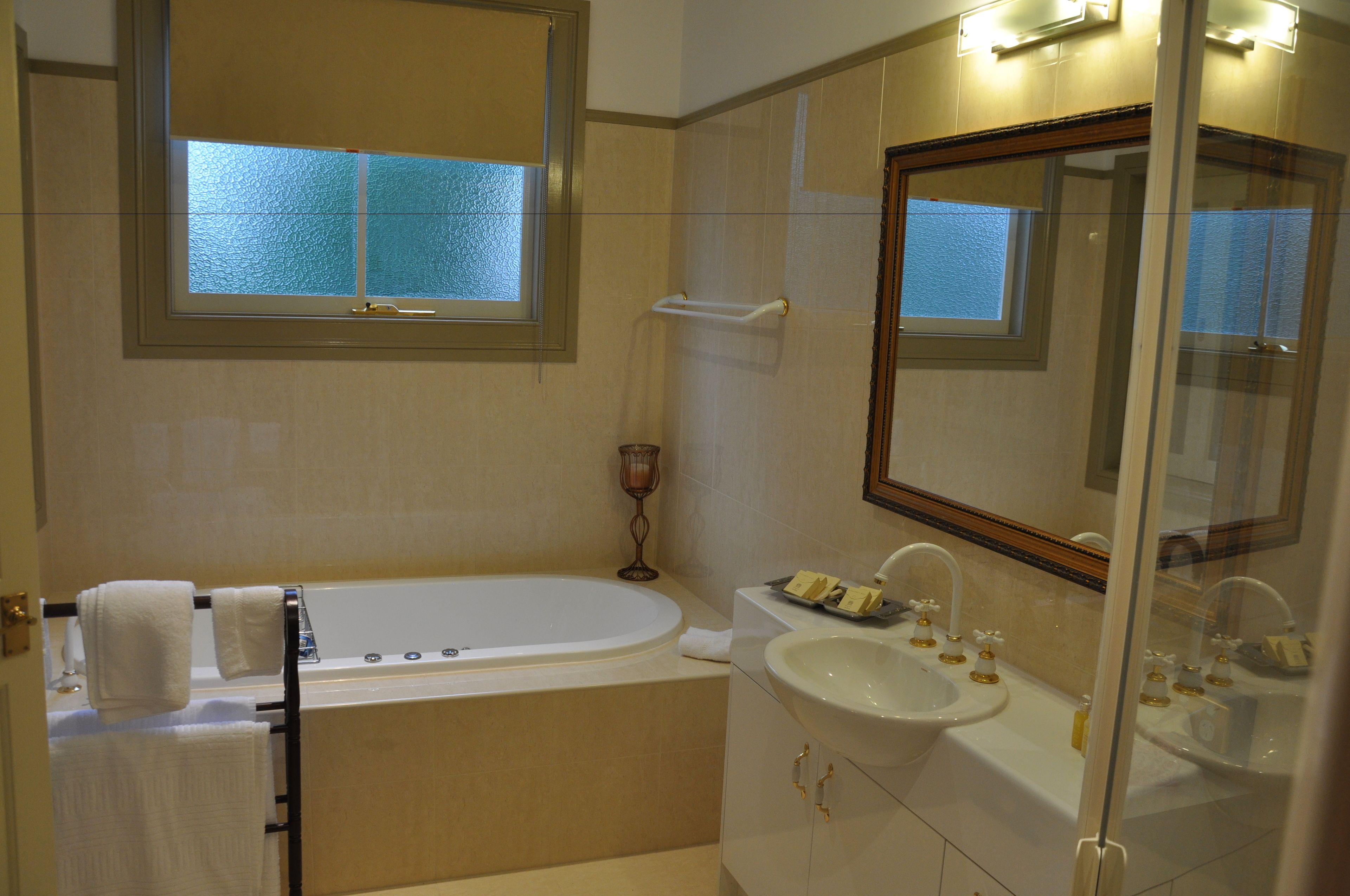 Ein Badezimmer mit Badewanne, zwei Waschbecken, einem Waschtisch, einem Fenster und einem Spiegel.