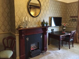 A room with a fireplace, a television, a dining table with chairs, and a mirror on the wall.