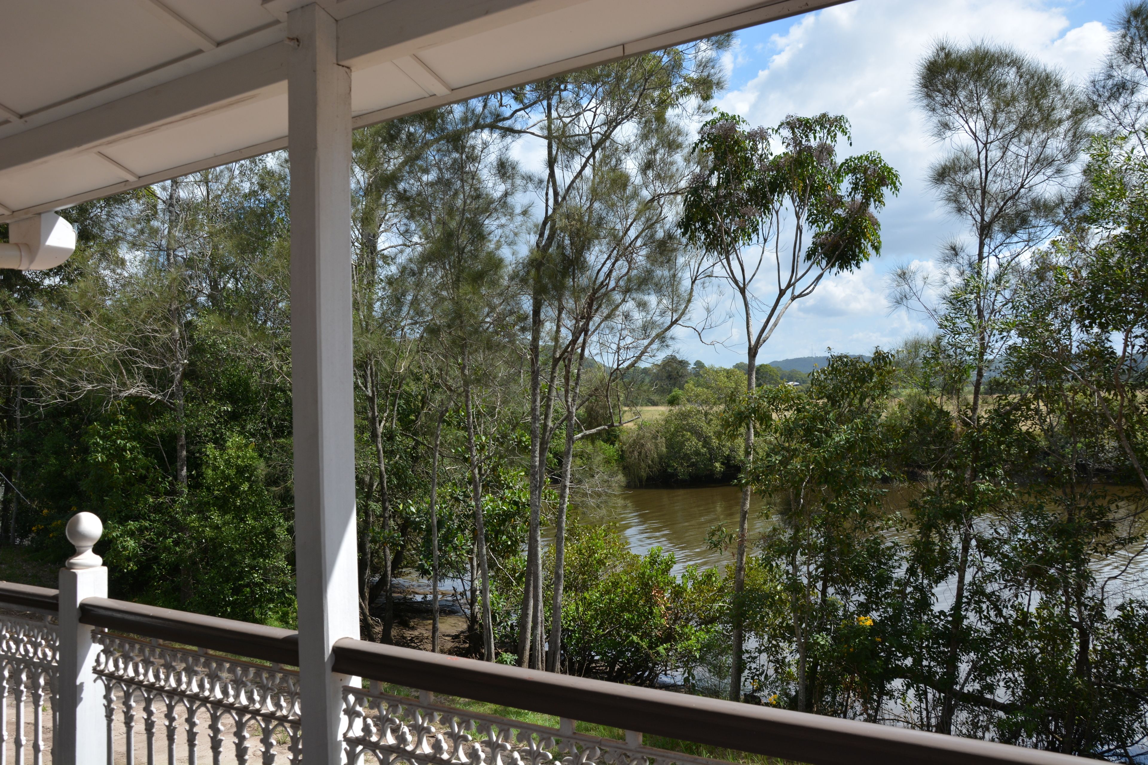 Blick vom Balkon auf einen Fluss, Bäume und einen klaren Himmel.