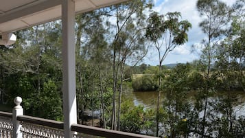 Blick vom Balkon auf einen Fluss, Bäume und einen klaren Himmel.