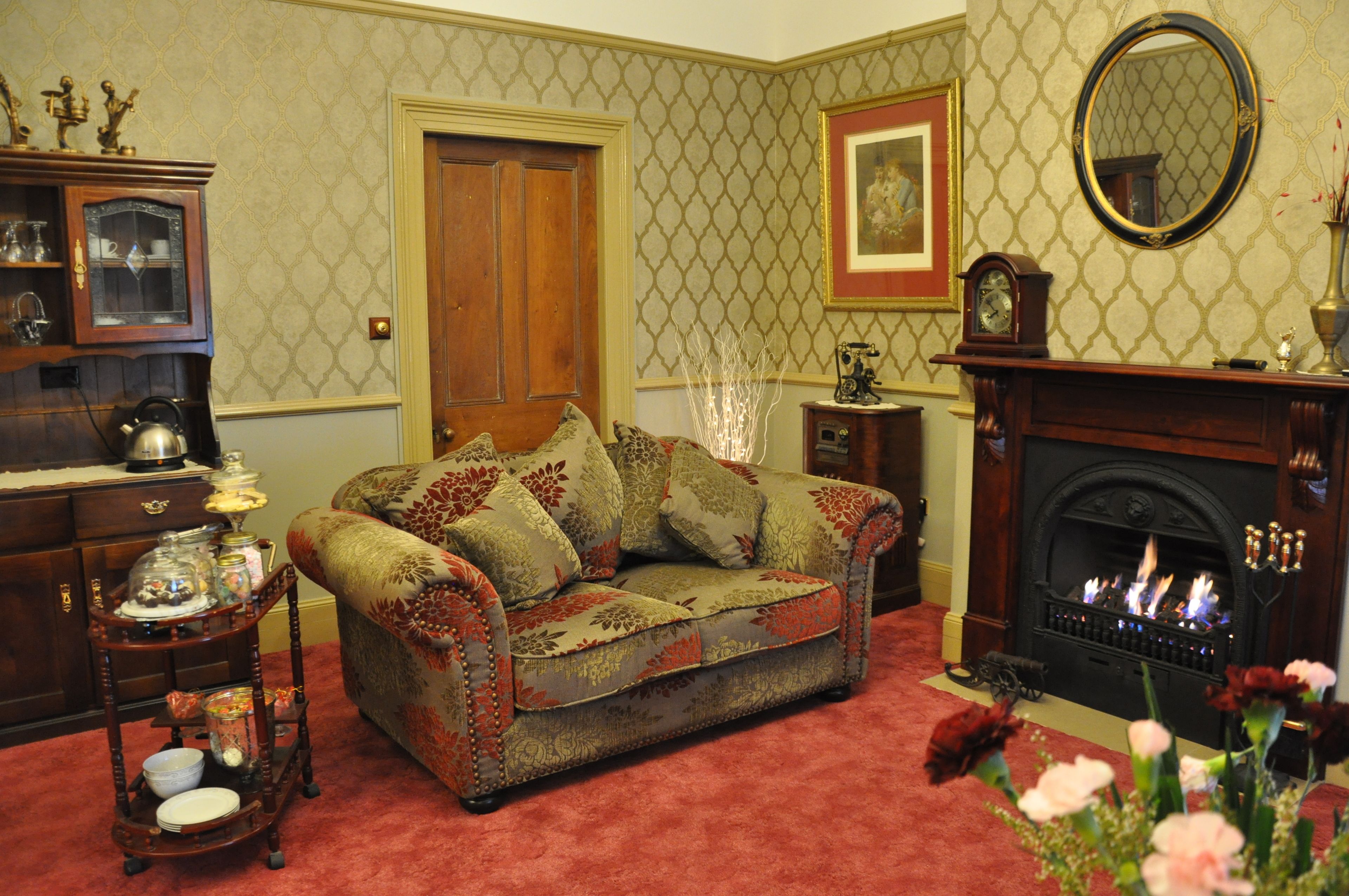 A cozy living room with a patterned sofa, a fireplace, and a wooden cabinet.
