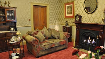 A cozy living room with a patterned sofa, a fireplace, and a wooden cabinet.