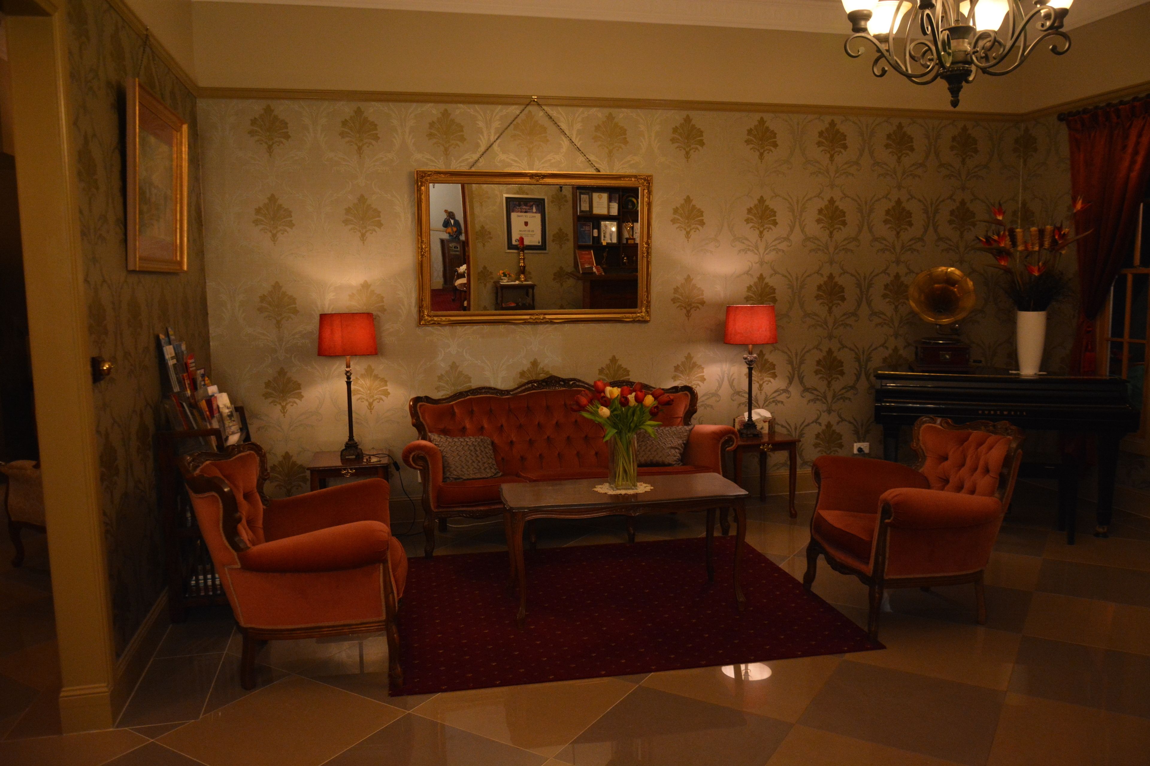 A living room with a red sofa, two armchairs, a coffee table, and a piano.