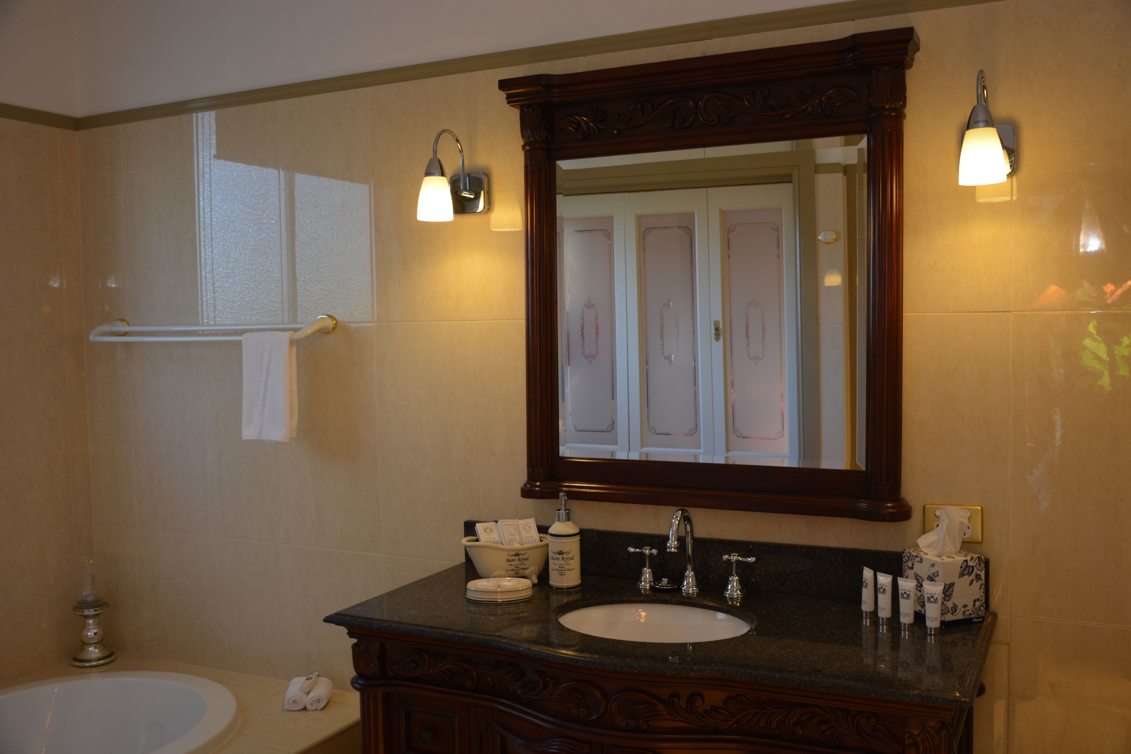 Een badkamer met een bad, wastafel, spiegel en toiletartikelen.