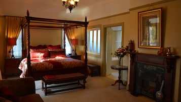 A four-poster bed with red bedding, a fireplace, and a chandelier.
