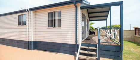 A mobile home with a covered porch and a small outdoor seating area.