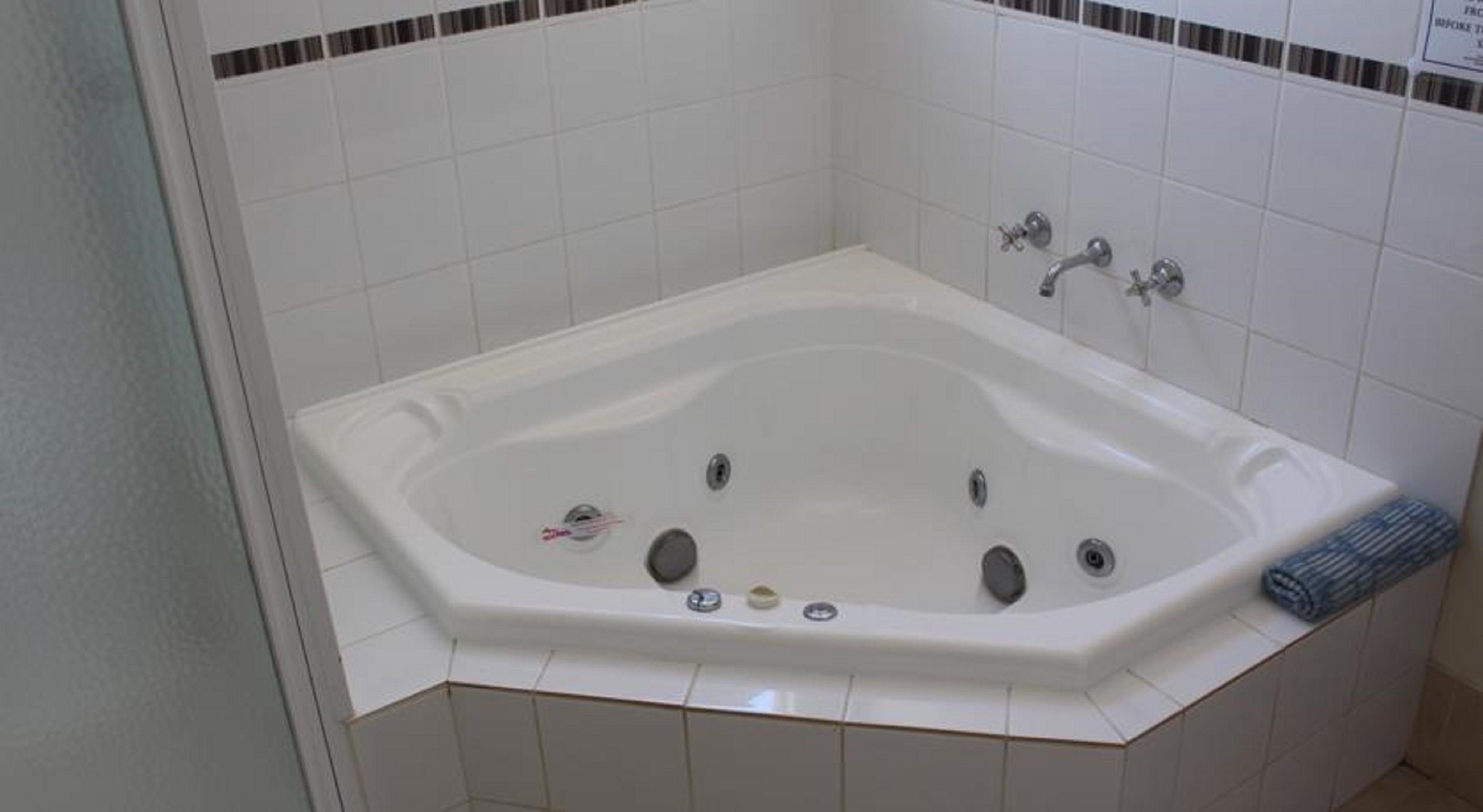 A standard hotel bathroom with a white bathtub, two faucets, and a single showerhead.