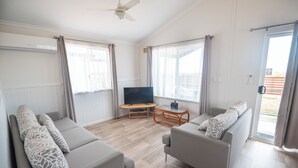 Un salon moderne avec deux canapés, un téléviseur et une petite table.
