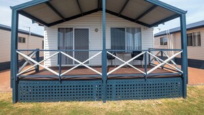 Une maison mobile dotée d’un porche couvert et d’une terrasse clôturée.