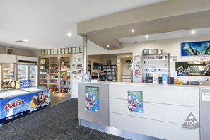 Zona de recepción con mostrador, refrigerador y exhibición de helados. Hay estanterías y un cartel que dice 'Top Parks'.
