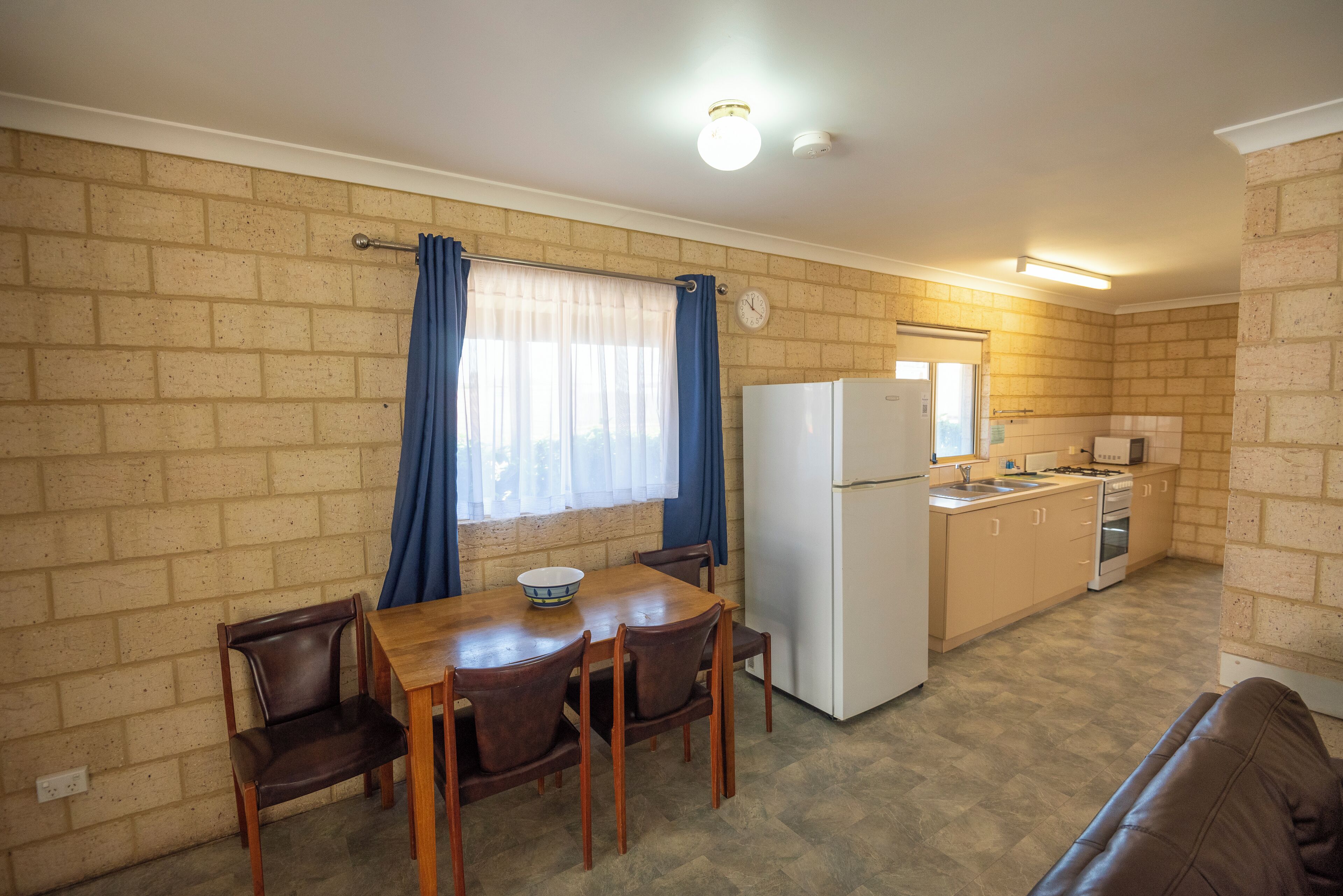 Una cocina compacta con comedor, un refrigerador, estufa y un reloj en la pared.