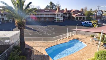Un hotel con piscina, patio cubierto y estacionamiento.
