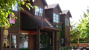 Un edificio de madera con múltiples ventanas y un patio cubierto con mesas de picnic.