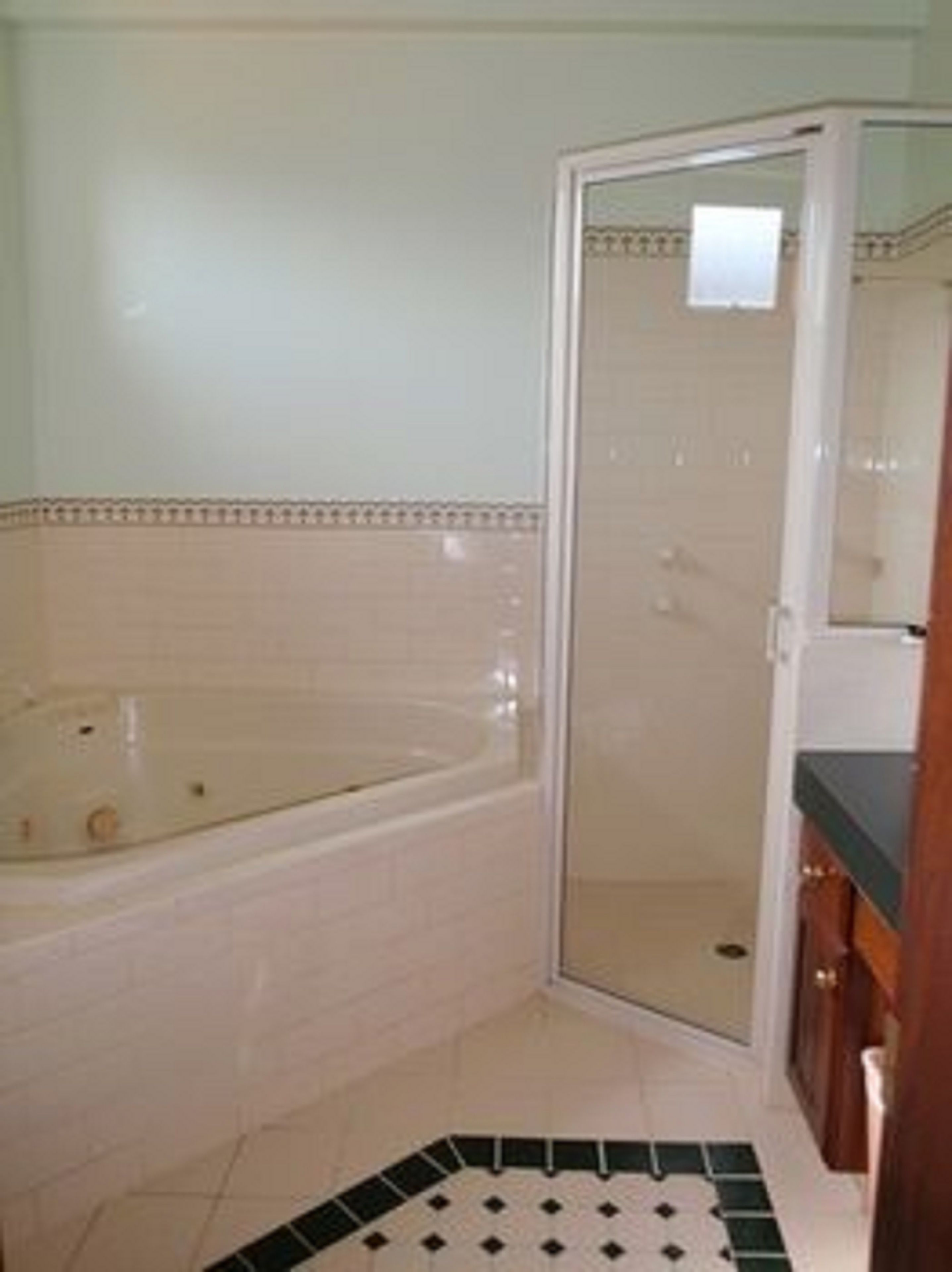 Une salle de bain avec une baignoire, un espace douche et un carrelage au sol.