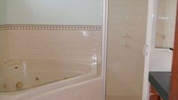 Un baño con bañera, cabina de ducha y piso cubierto de azulejos.
