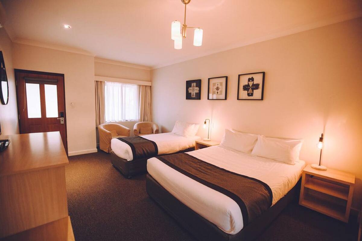 Een hotelkamer met twee bedden, een bureau, een stoel en een deur.