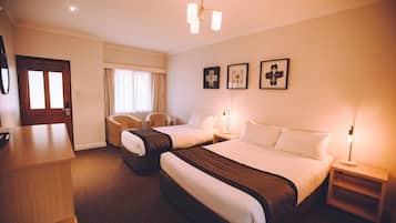 Una habitación de hotel con dos camas, un escritorio, una silla y una puerta.