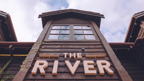 Un letrero de madera con la palabra 'THE RIVER' en la fachada de un edificio.
