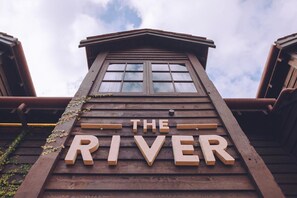 Un letrero de madera con la palabra 'THE RIVER' en la fachada de un edificio.
