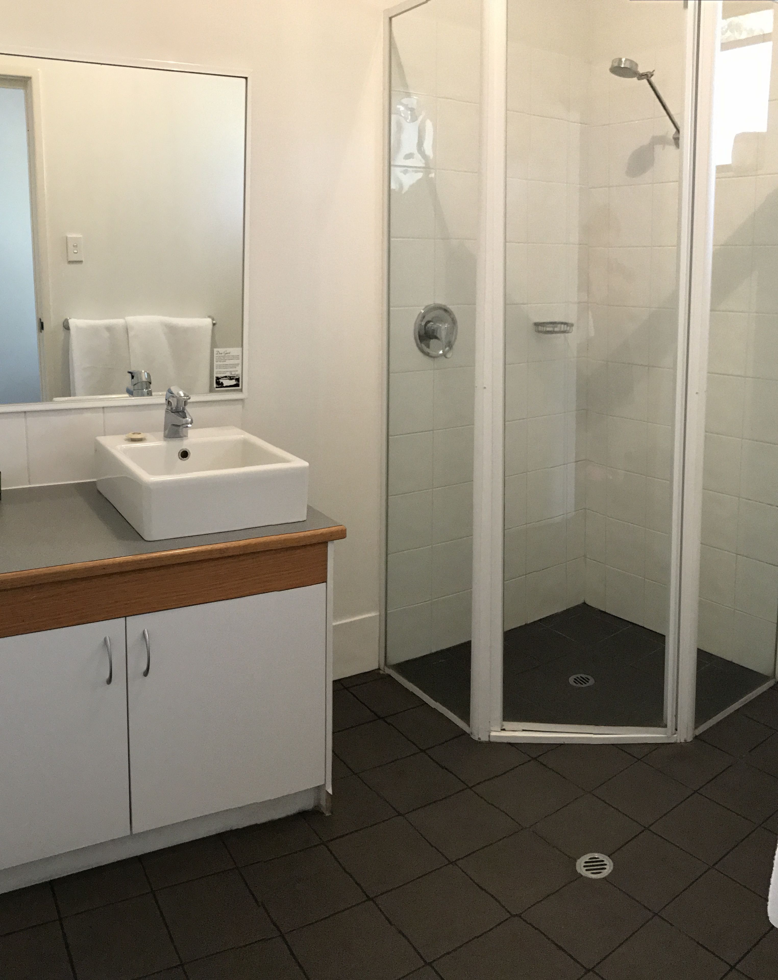 A bathroom with a white sink, mirror, and shower enclosure.