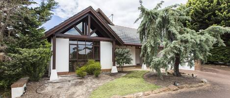 A modern house with a sloped roof, large windows, and a well-maintained lawn.