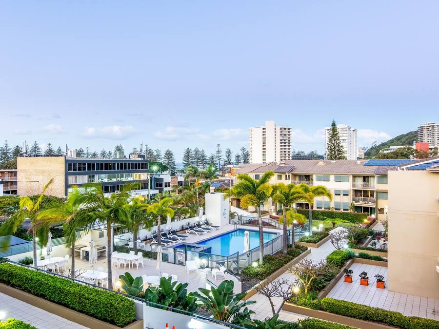 A hotel with a swimming pool, outdoor seating, and lush landscaping.
