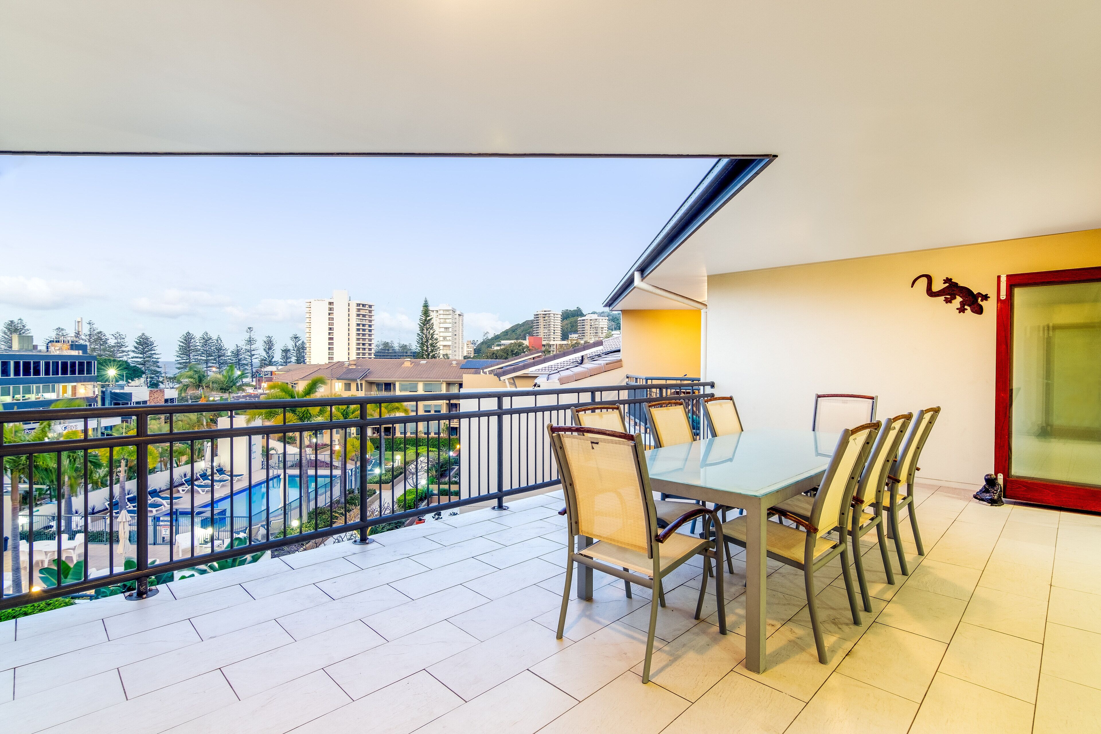 Ein Balkon mit Esstisch und Stühlen, mit Blick auf einen Pool und Gebäude.
