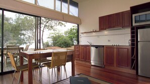 A modern kitchen with wooden cabinets, stainless steel appliances, and a dining area with wicker chairs. - NRMA Myall Shores Holiday Park (Bombah Point)