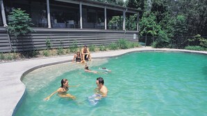 A swimming pool with people in it, surrounded by a building with large windows and a covered area. - NRMA Myall Shores Holiday Park (Bombah Point)