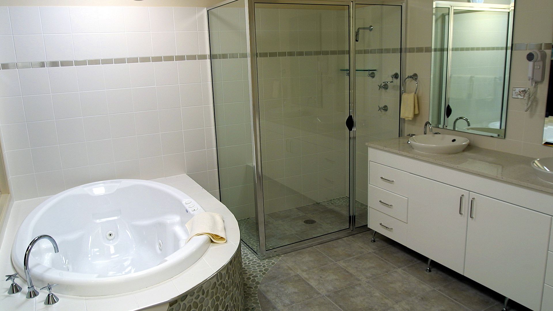 A bathroom with a white bathtub, a glass-enclosed shower, a sink, and a mirror.