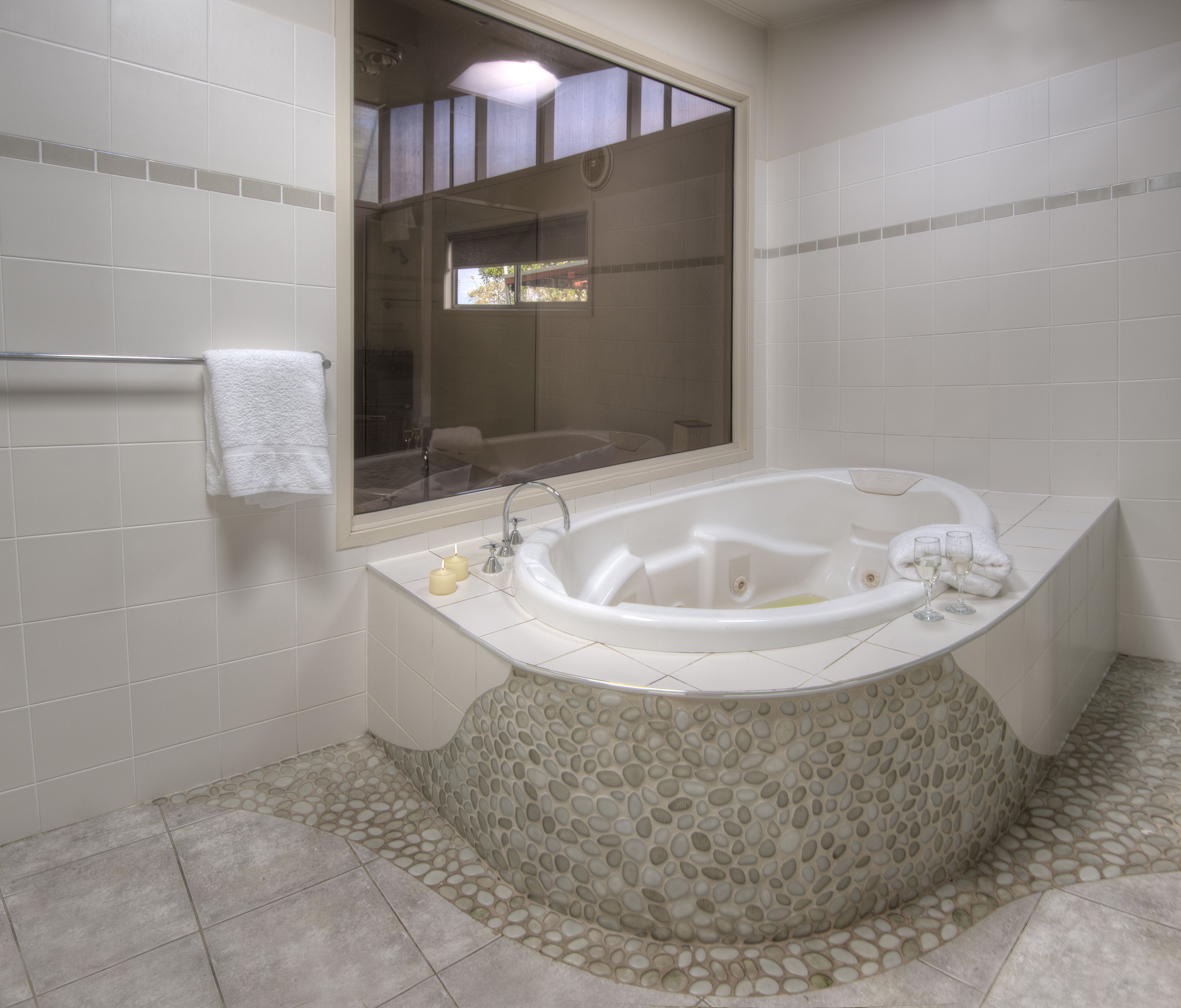 Une salle de bain avec une grande baignoire, une fenêtre et un sol carrelé.