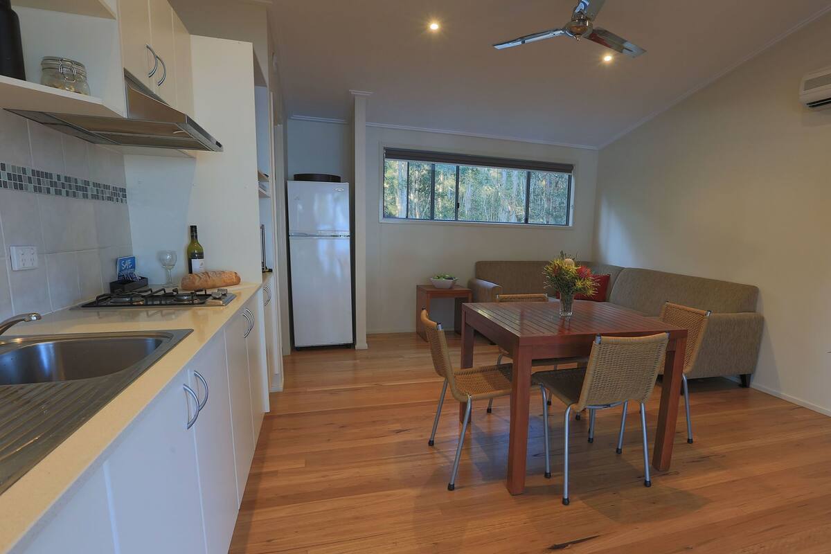 Une cuisine moderne avec un coin repas, un plancher en bois et un ventilateur de plafond.