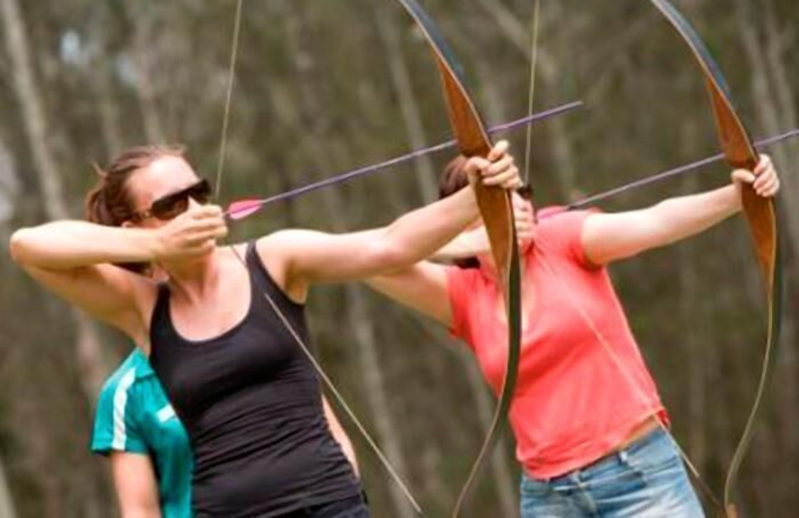 Two people archery in a forest.