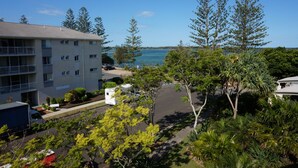 A multi-story building with a balcony on the left, surrounded by lush greenery and a view of the sea. - Moorings Beach Resort (Golden Beach)