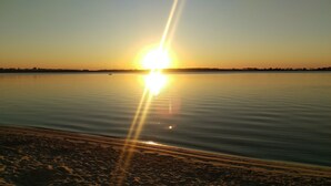 A beach with a calm sea, a clear sky, and the sun setting or rising. - Moorings Beach Resort (Golden Beach)