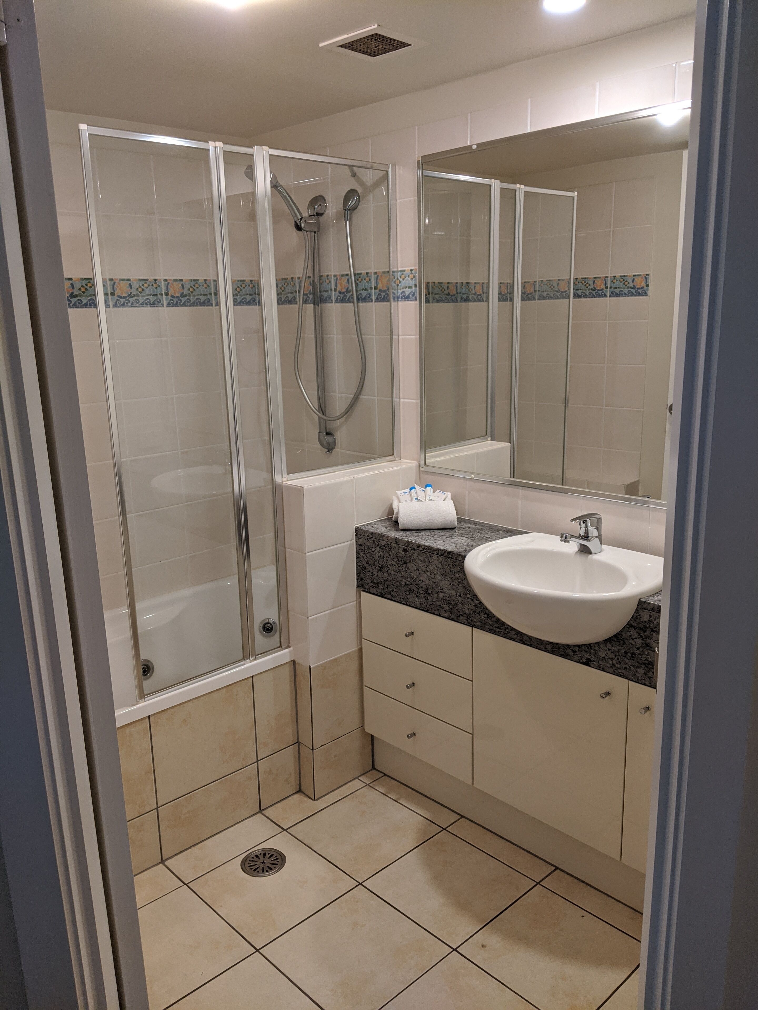 A bathroom with a glass-enclosed shower, a sink, and a mirror.