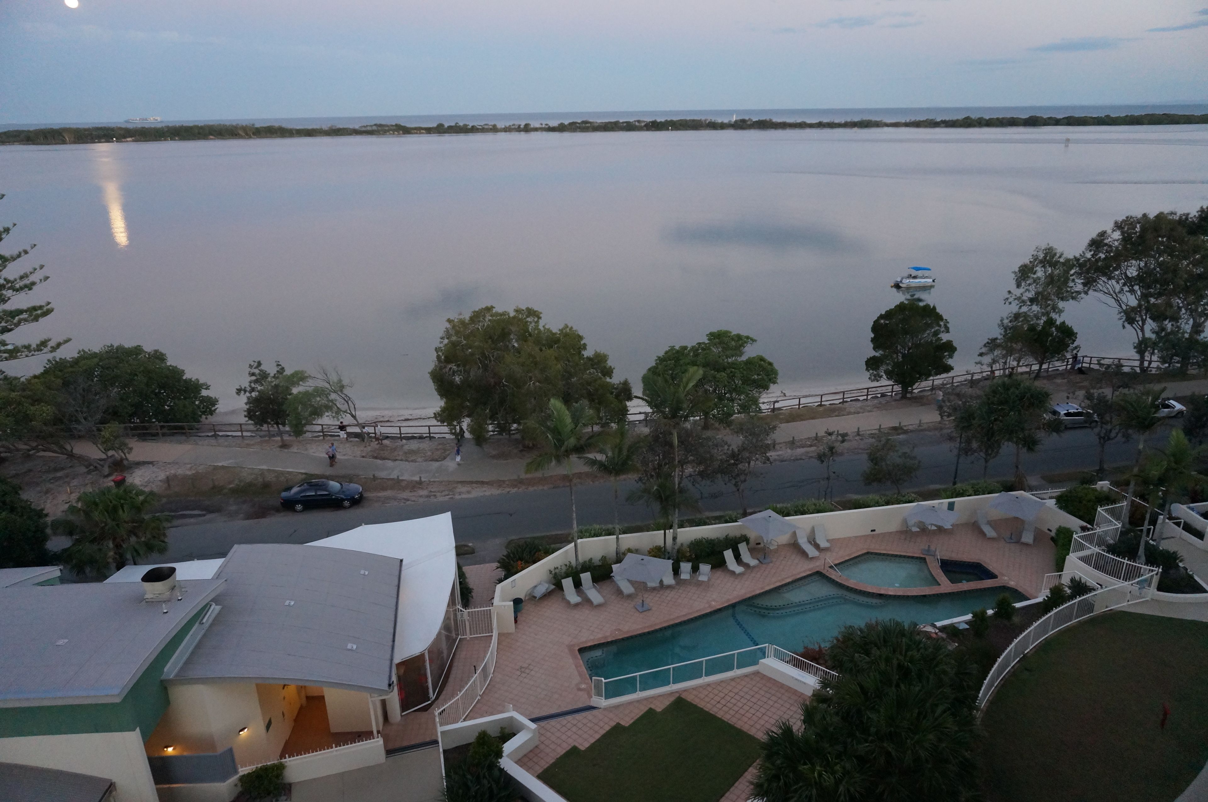 Um resort com piscina, cadeiras de sol e vista para um lago tranquilo.