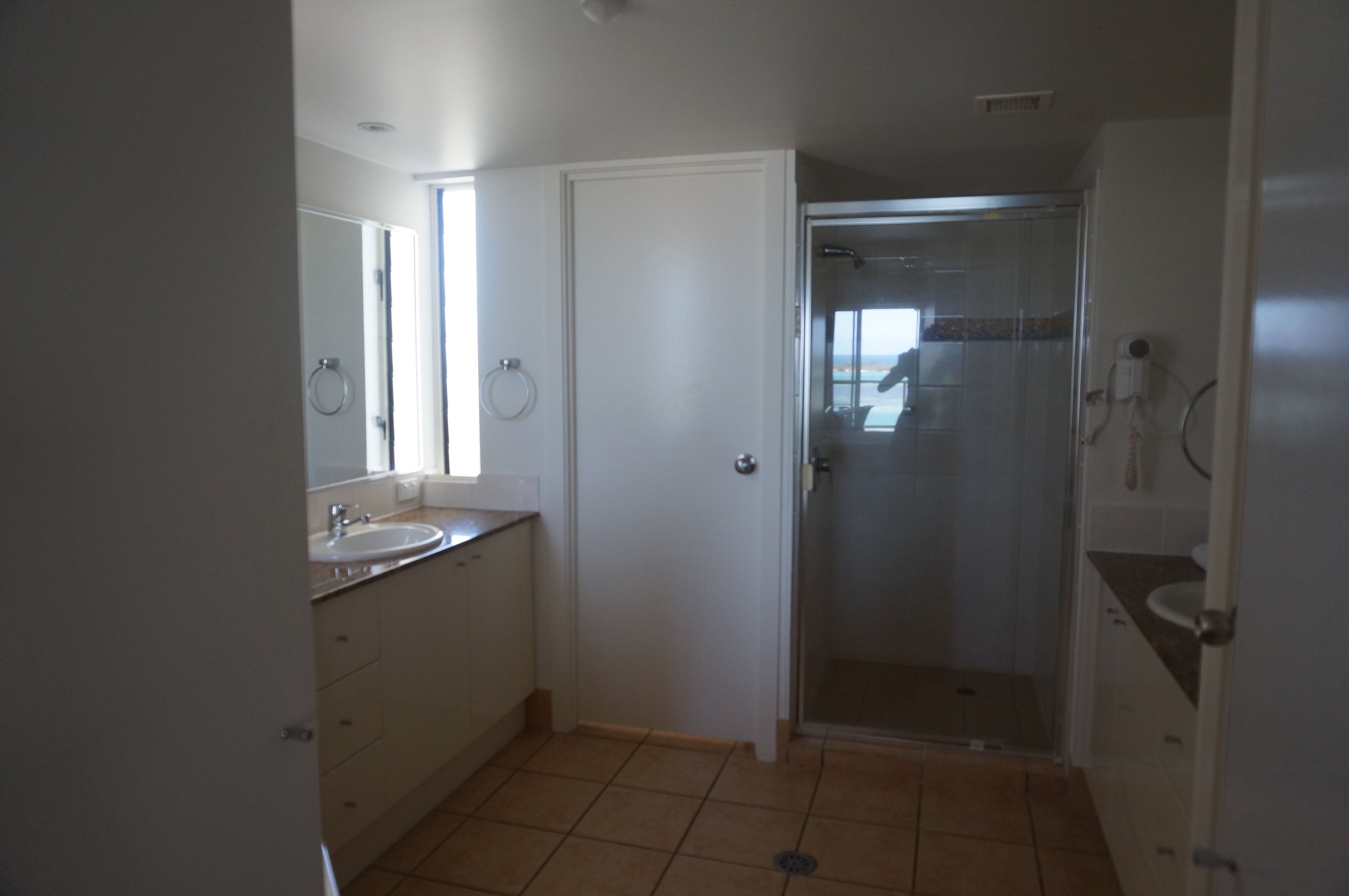 A bathroom with a shower, a sink, and a mirror.