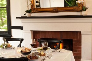 A dining table set for a meal with a fireplace in the background. - The Dormie House - On The Golf Course (Moss Vale)