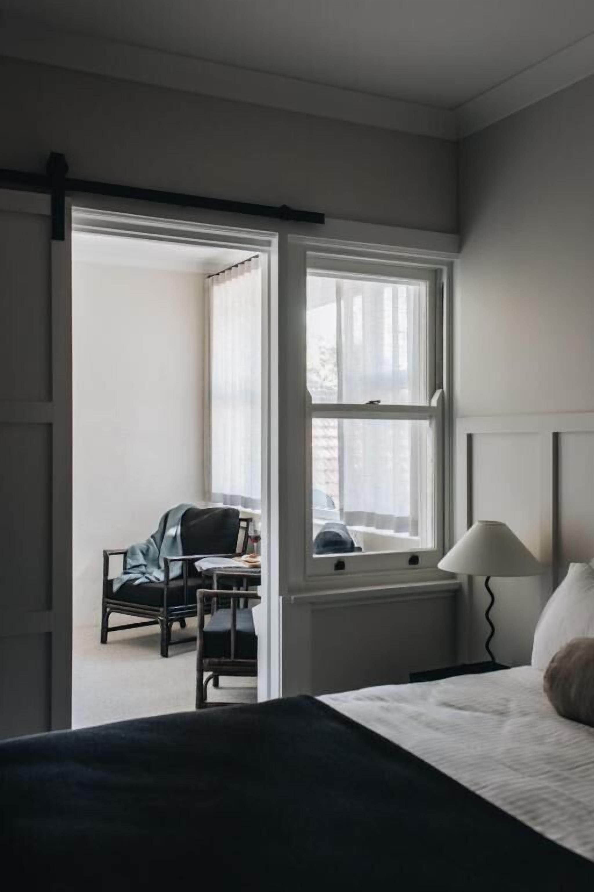 Une chambre d’hôtel avec un lit, un bureau, une chaise et une fenêtre.