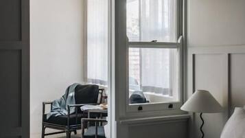Une chambre d’hôtel avec un lit, un bureau, une chaise et une fenêtre.