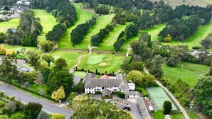 An aerial view of a golf course with a clubhouse and tennis courts. - The Dormie House - On The Golf Course (Moss Vale)