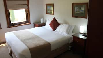 A neatly made bed with a brown accent pillow, a bedside table with a lamp, and two framed pictures on the wall.