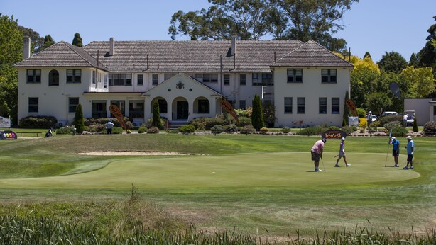 A golf course with a clubhouse featuring a symmetrical facade, arched windows, and a central entrance. - The Dormie House - On The Golf Course (Moss Vale)