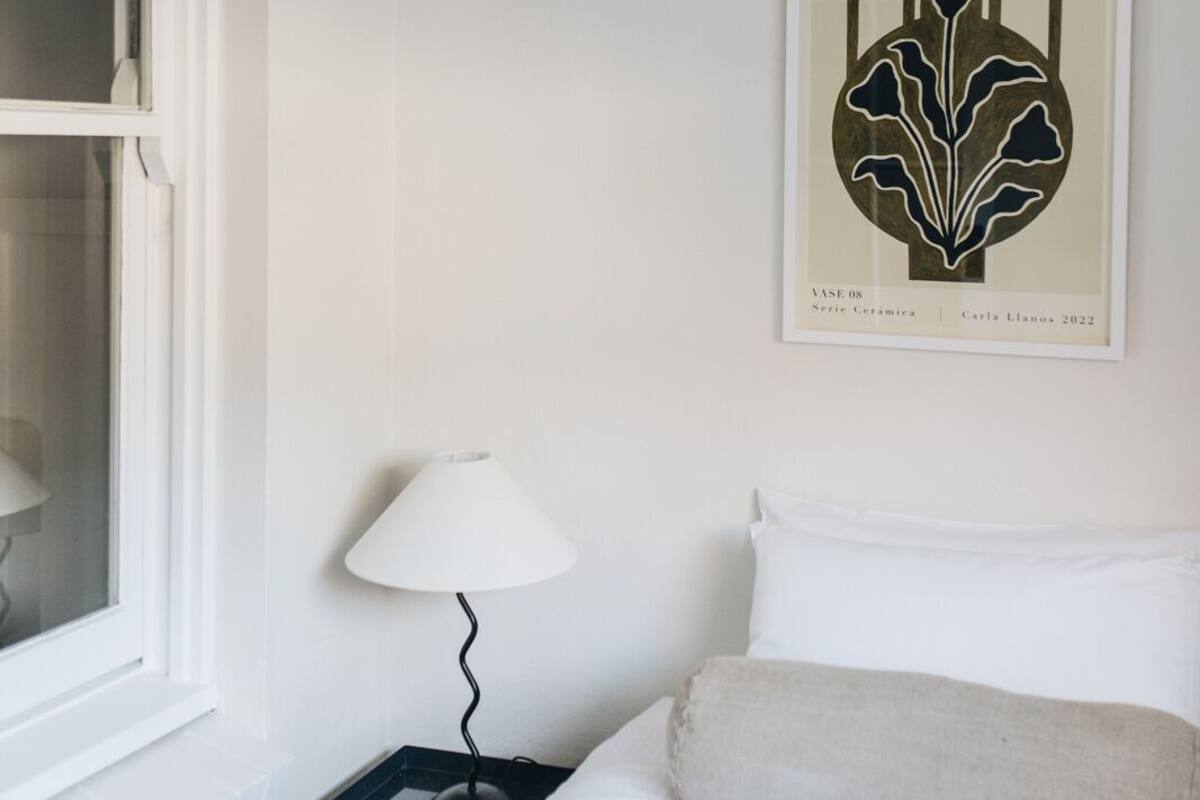 A hotel room with a bed, a nightstand, a lamp, and a framed artwork on the wall.