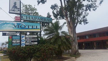 Señal de motel que ofrece múltiples servicios, incluyendo aire acondicionado, televisión por cable y WiFi gratuito.