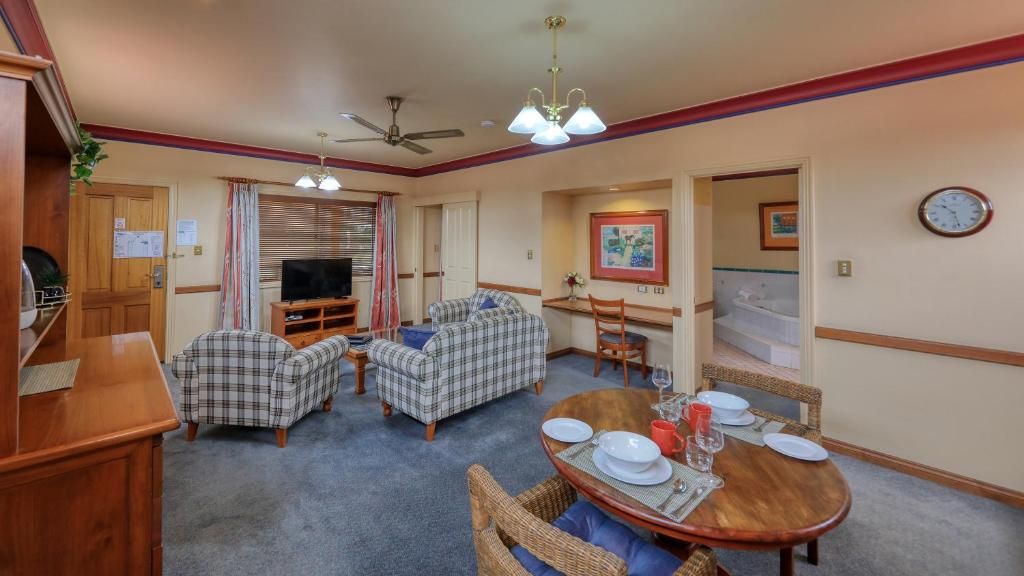 A compact living space with a dining area, a sofa, a television, and a clock on the wall.